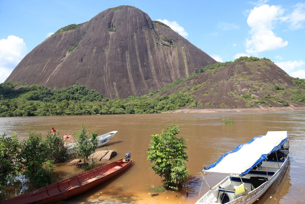 Foto de en la que se ve tres lanchas a orillas del río Inirida, Guainia y al fondo la rocas del sector de Mavecure