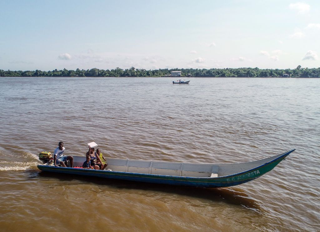 Fotografía tomada con un dron en la que se ven tres personas a bordo de un motor canoa navegando por el río Guapi