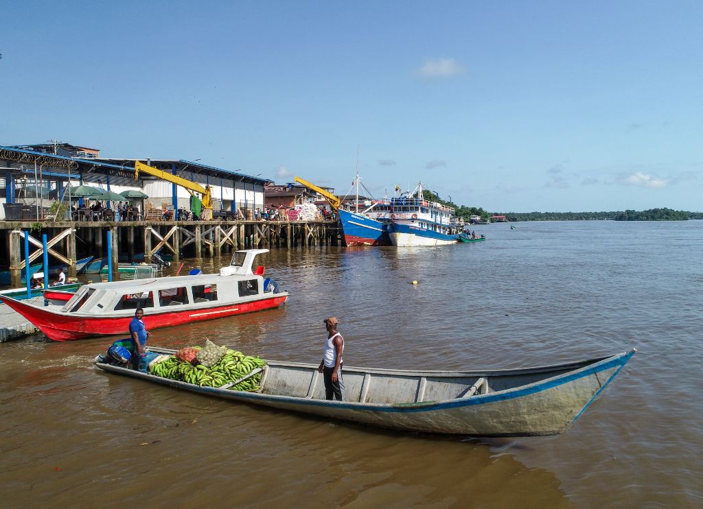 Fotografía tomada con un dron en la que se ve a dos hombres transportando plátanos en un motor canoa en el río Guapi