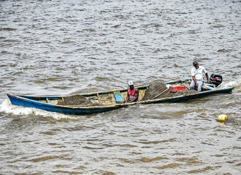 Aerofotografía en la que se aprecia a dos hombres transportando arena abordo de una embarcación en el río Guapi