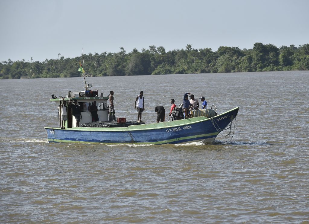 Embarcación mediana con pescadores navegando el río Guapi en Cauca, representando la pesca y el transporte fluvial como medios tradicionales de vida en la región.